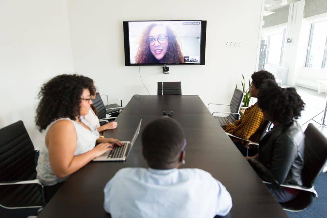 A group of employees participate in a conference call with a fellow colleague.