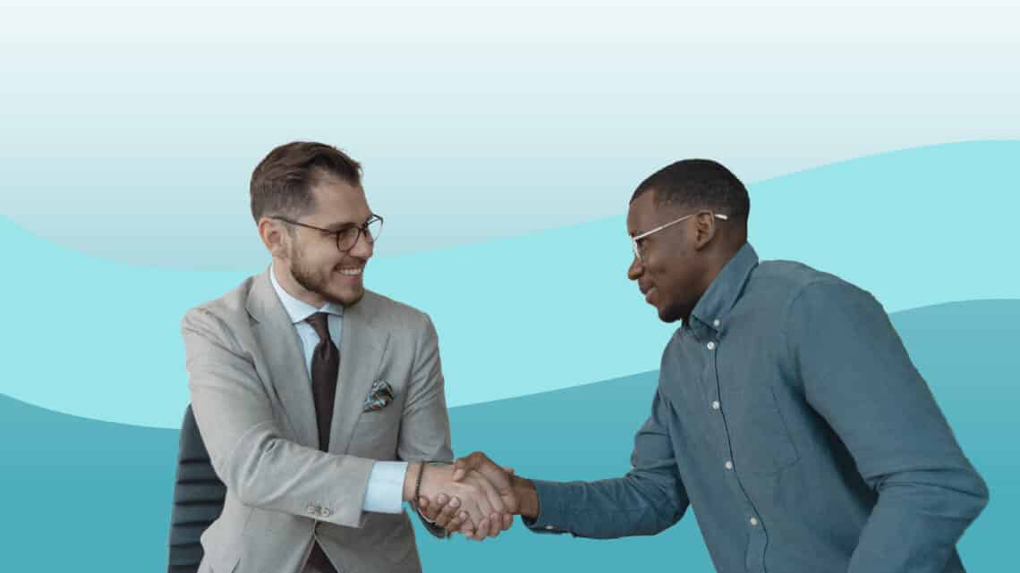 Two young businessmen shake hands with each other as if in agreement or introduction
